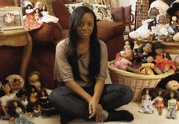 Jillian Knowles em still do documentário da irmã, posando com a coleção de bonecas das duas.